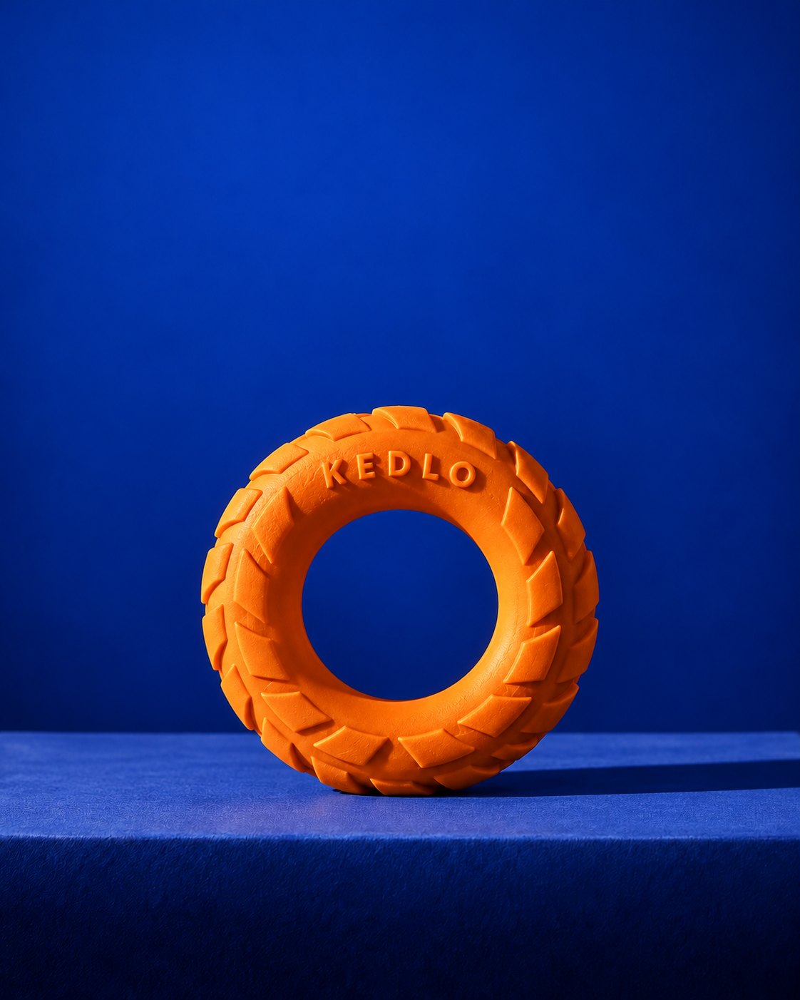 An orange rubber chew ring on a blue block, blue background